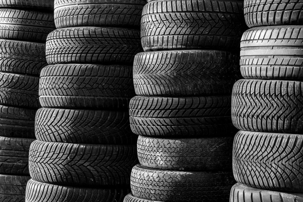 pexels-photo-37002235-37002235 Black and white image of stacked vehicle tires showcasing various tread patterns.