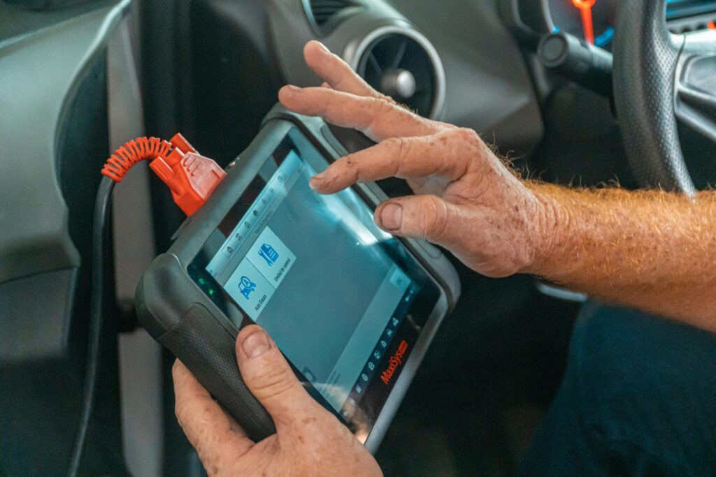 pexels-photo-4116193-4116193 Mechanic using a diagnostic tool inside a car to check for engine issues and ensure proper maintenance.