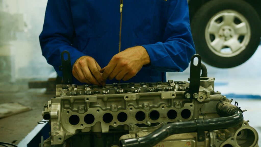 pexels-photo-8985664-8985664 Close-up of a mechanic repairing an engine in a garage setting.